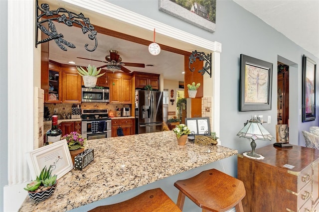 kitchen featuring appliances with stainless steel finishes, backsplash, a kitchen breakfast bar, hanging light fixtures, and kitchen peninsula