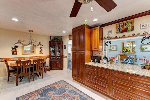 kitchen with decorative light fixtures, light stone countertops, decorative backsplash, and a textured ceiling