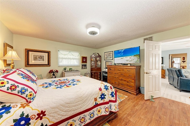 bedroom with multiple windows, wood-type flooring, and a textured ceiling