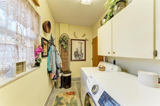 washroom featuring cabinets, a textured ceiling, and washing machine and clothes dryer