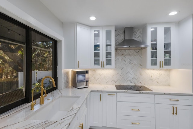 kitchen featuring sink, wall chimney exhaust hood, decorative backsplash, black electric stovetop, and white cabinets