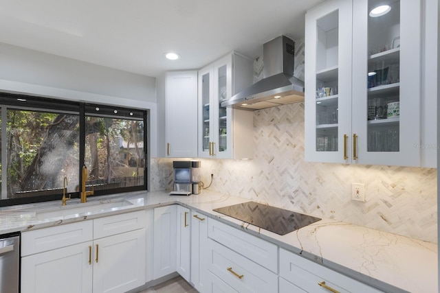 kitchen featuring white cabinetry, sink, light stone counters, and wall chimney range hood