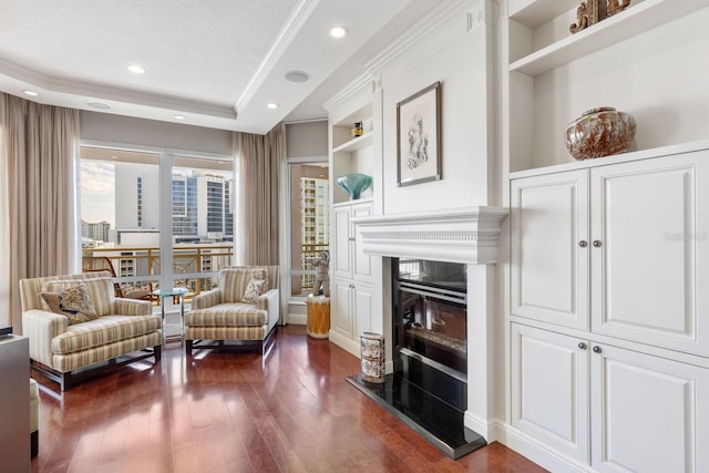 living area featuring built in features, dark hardwood / wood-style floors, crown molding, a textured ceiling, and a tray ceiling