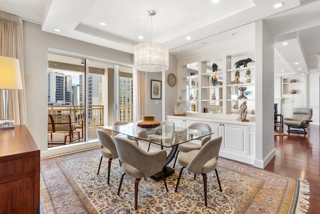 dining area featuring built in shelves, a raised ceiling, wood-type flooring, and a fireplace