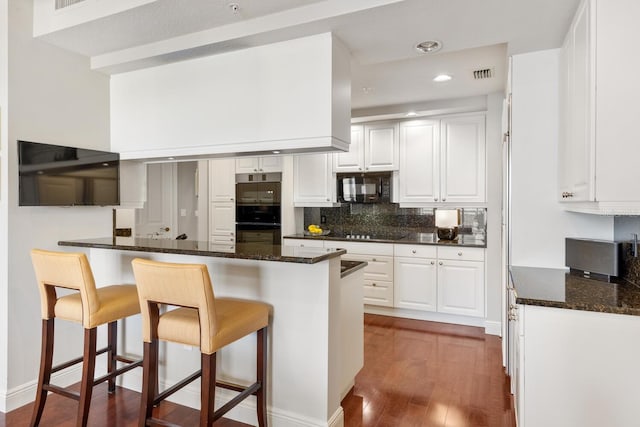 kitchen featuring a kitchen breakfast bar, kitchen peninsula, white cabinetry, and black appliances