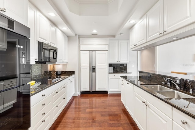 kitchen featuring dark stone counters, white cabinets, and black appliances