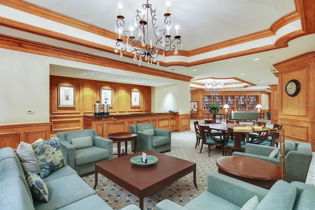 living room featuring a raised ceiling, a notable chandelier, and ornamental molding