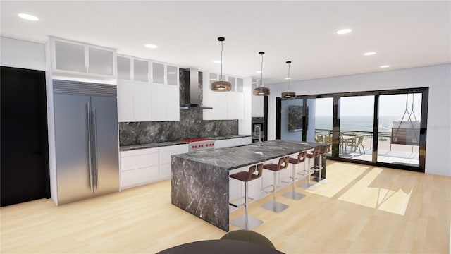 kitchen featuring white cabinetry, a center island, wall chimney exhaust hood, stainless steel appliances, and a water view