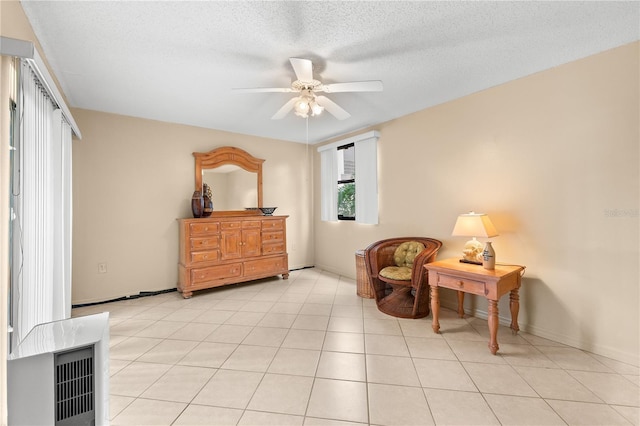 living area with ceiling fan, light tile patterned floors, and a textured ceiling