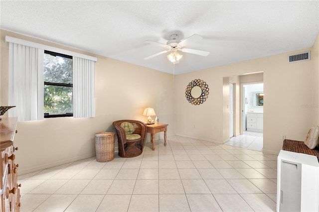 living area featuring ceiling fan, light tile patterned flooring, and a textured ceiling