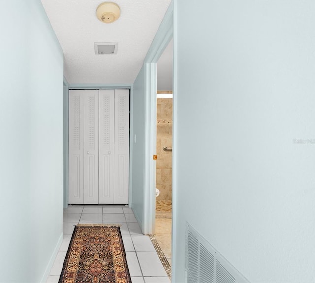 hall featuring a textured ceiling and light tile patterned flooring