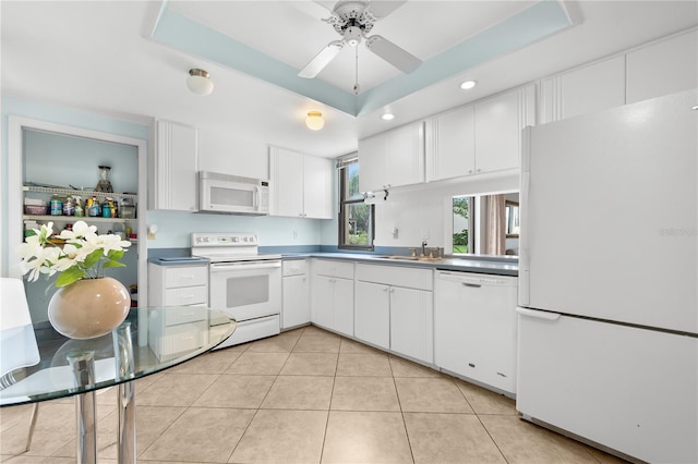 kitchen featuring white appliances, sink, ceiling fan, a tray ceiling, and white cabinetry