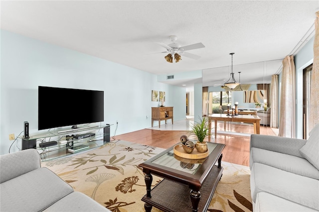 living room featuring ceiling fan, light hardwood / wood-style floors, and a textured ceiling