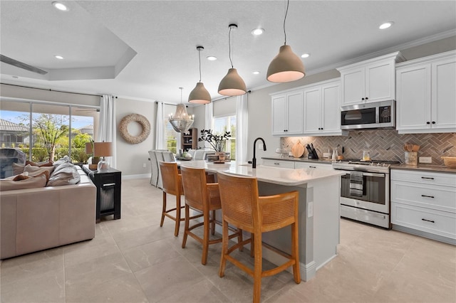 kitchen with a center island with sink, white cabinetry, hanging light fixtures, and appliances with stainless steel finishes