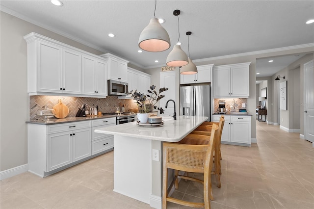 kitchen featuring white cabinets, pendant lighting, stainless steel appliances, and a center island with sink