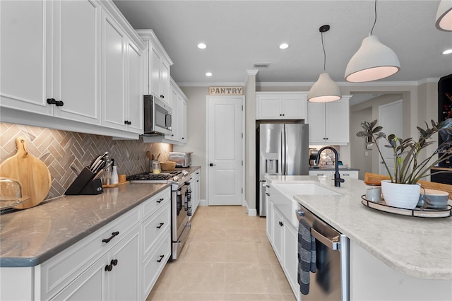 kitchen with appliances with stainless steel finishes, tasteful backsplash, ornamental molding, pendant lighting, and white cabinetry