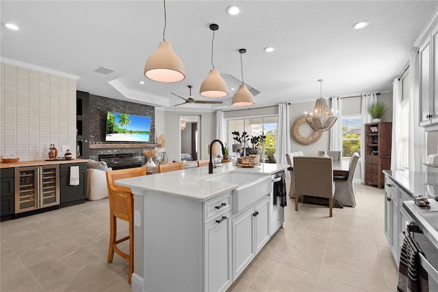 kitchen featuring a raised ceiling, sink, white cabinetry, wine cooler, and hanging light fixtures