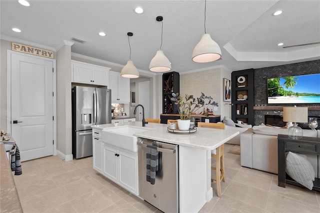 kitchen with sink, stainless steel appliances, an island with sink, decorative light fixtures, and white cabinets