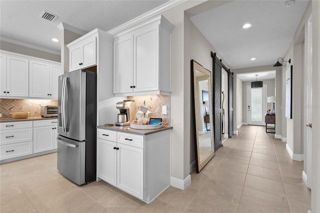 kitchen with backsplash, a barn door, white cabinetry, and stainless steel refrigerator with ice dispenser