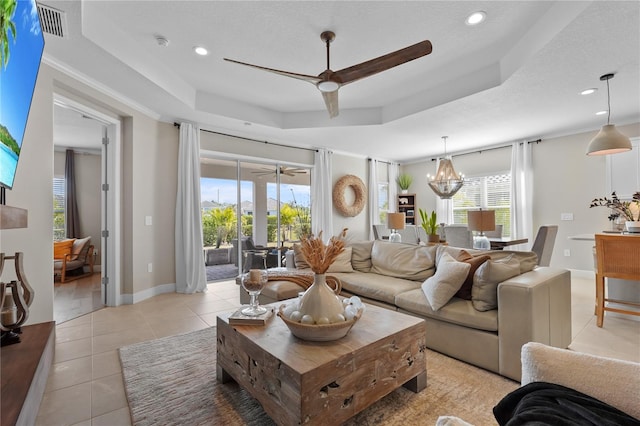 living room featuring a tray ceiling, light tile patterned floors, and an inviting chandelier