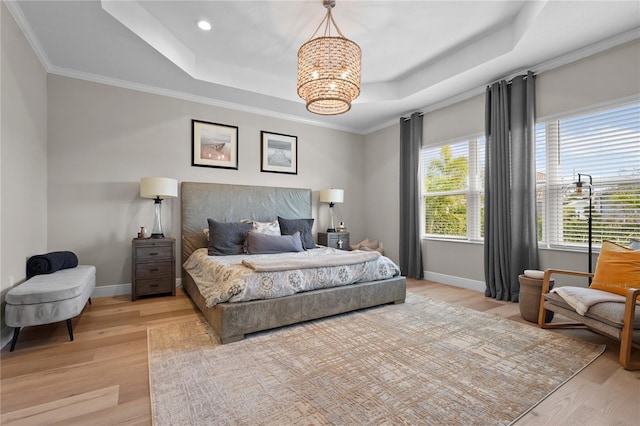 bedroom featuring an inviting chandelier, light wood-type flooring, crown molding, and a tray ceiling