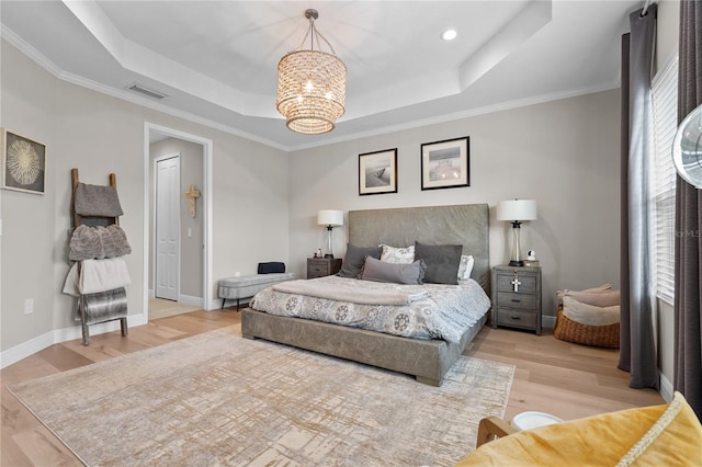 bedroom featuring ornamental molding, a tray ceiling, an inviting chandelier, and light hardwood / wood-style floors