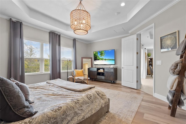 bedroom featuring a raised ceiling, ornamental molding, light hardwood / wood-style floors, and a notable chandelier