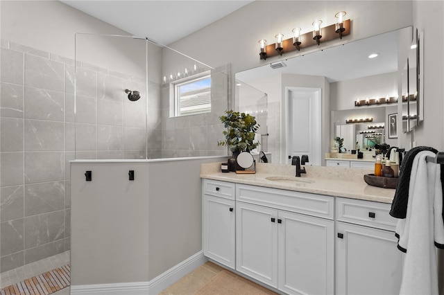 bathroom featuring tile patterned floors, vanity, and a tile shower