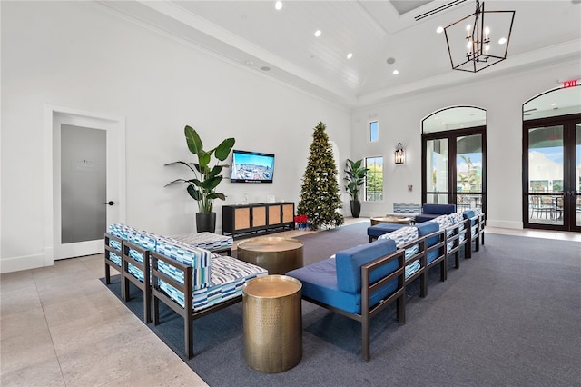 living room featuring french doors, a high ceiling, an inviting chandelier, a tray ceiling, and ornamental molding