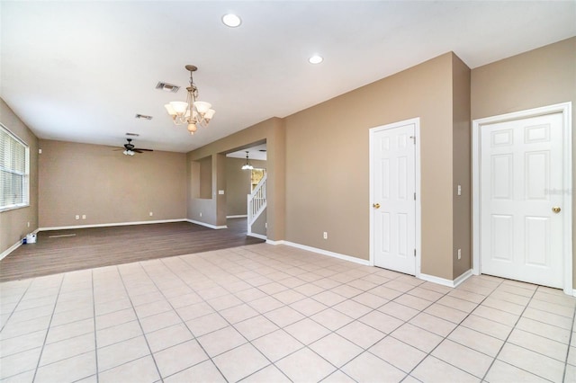 empty room with light tile patterned floors and ceiling fan with notable chandelier