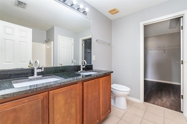 bathroom featuring tile patterned flooring, vanity, toilet, and walk in shower