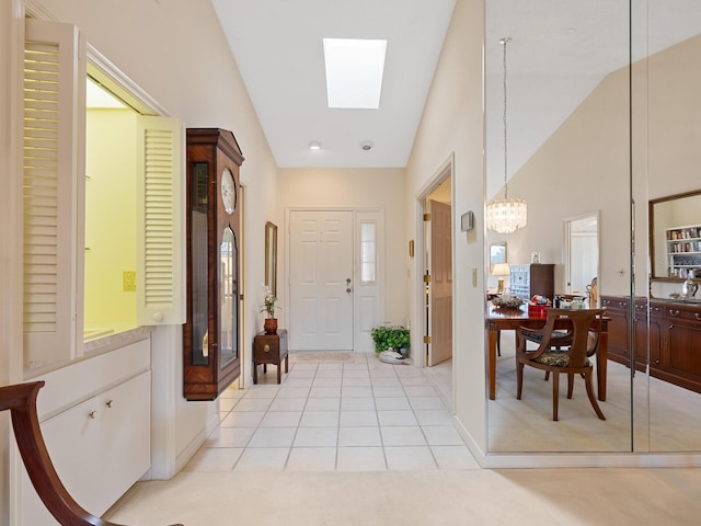 foyer featuring high vaulted ceiling, light tile patterned floors, a skylight, and a chandelier