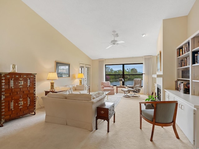 carpeted living room with ceiling fan and high vaulted ceiling