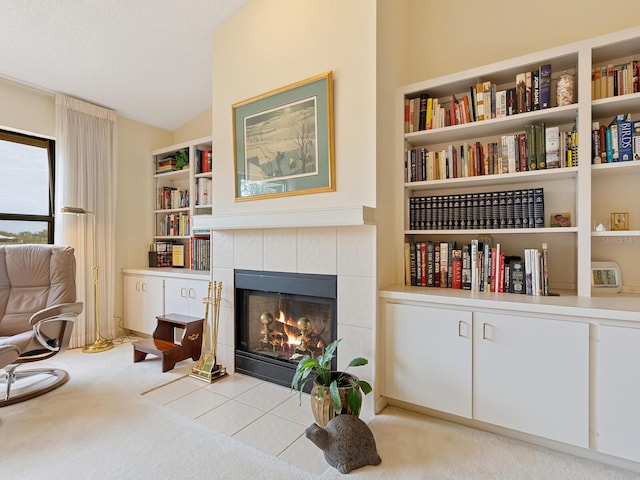 living area featuring light colored carpet, a tiled fireplace, and vaulted ceiling