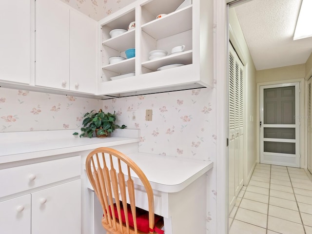 kitchen featuring white cabinets, light tile patterned floors, and a textured ceiling