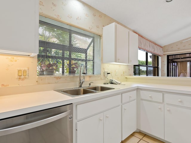 kitchen with lofted ceiling, dishwasher, sink, white cabinetry, and light tile patterned floors