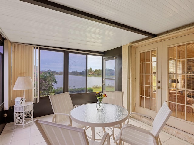 sunroom featuring a water view and french doors