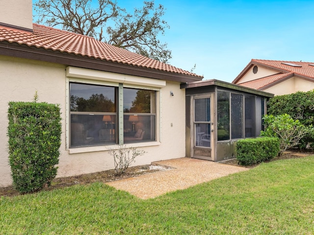 back of property featuring a sunroom and a lawn