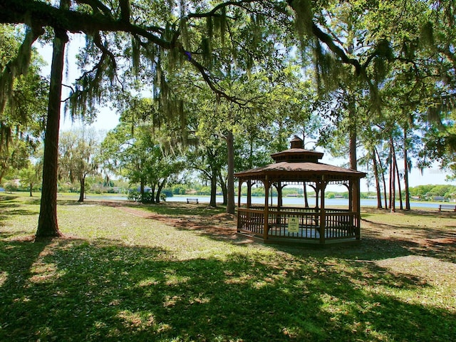 surrounding community with a water view, a gazebo, and a lawn