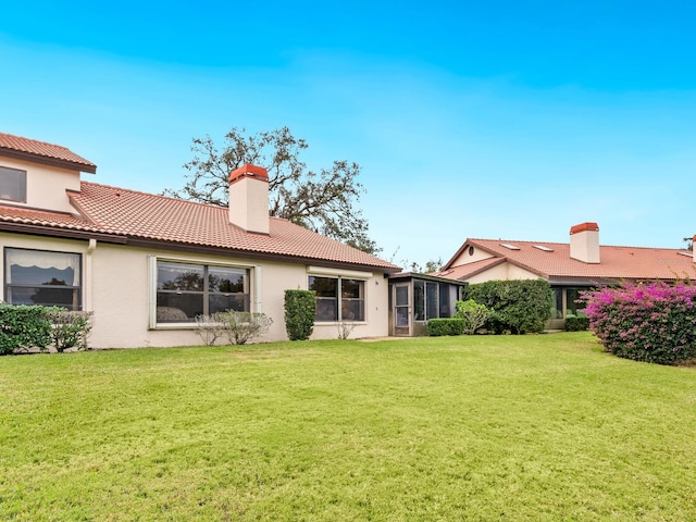 back of property with a sunroom and a lawn