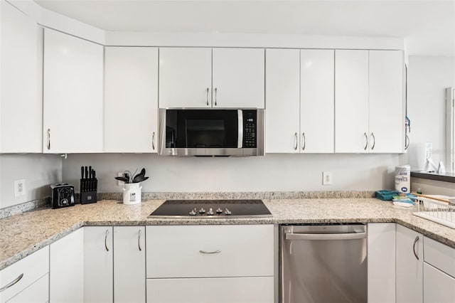 kitchen with white cabinets, stainless steel appliances, and light stone counters