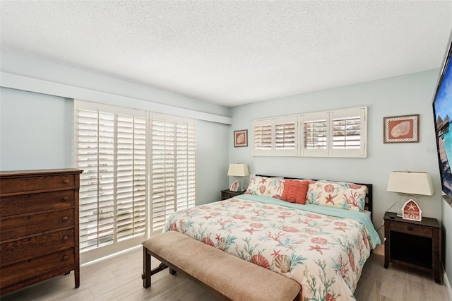 bedroom with a textured ceiling and light wood-type flooring