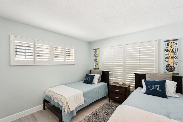 bedroom with light wood-type flooring and a textured ceiling