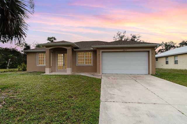 view of front of property featuring a lawn, a garage, and french doors