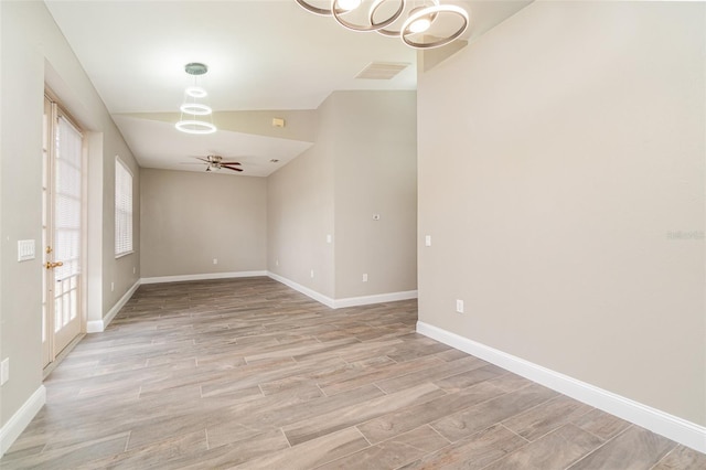 spare room featuring ceiling fan with notable chandelier