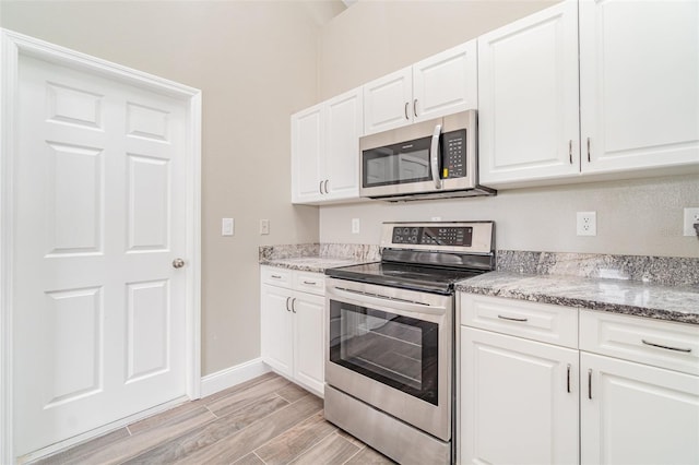 kitchen with light stone countertops, white cabinetry, and stainless steel appliances