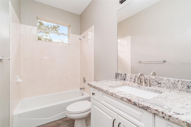 full bathroom with hardwood / wood-style floors, vanity, tiled shower / bath combo, and toilet