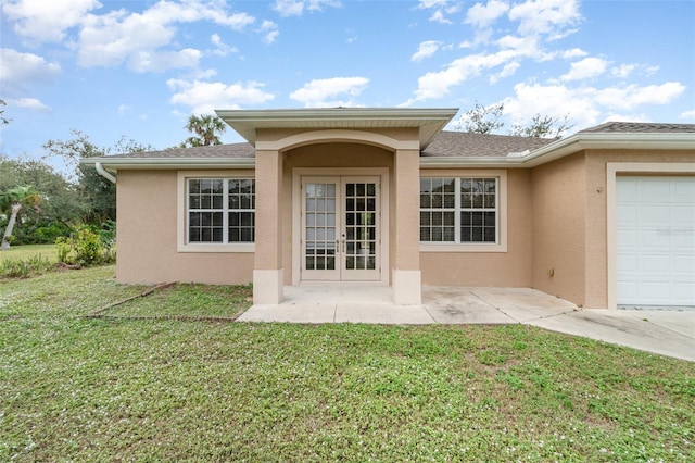 entrance to property with french doors, a yard, and a garage