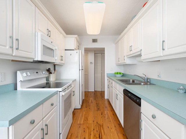 kitchen with light countertops, visible vents, white cabinets, a sink, and white appliances