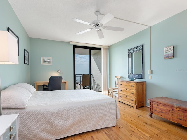 bedroom featuring light wood-style floors, ceiling fan, expansive windows, and access to outside